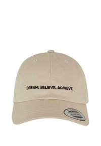 Cappellino da baseball beige in cotone con visiera curva. Presenta il testo ricamato in nero "DREAM. BELIEVE. ACHIEVE." sul davanti. Fascetta regolabile.