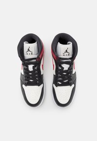 Paire de baskets montantes noires, blanches et rouges avec des lacets noirs et le logo Air Jordan sur la languette, vues de dessus sur fond blanc.