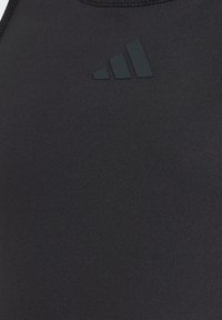 Μαύρο αθλητικό τοπ χωρίς μανίκια από απαλό, ελαστικό ύφασμα. Διαθέτει διακριτικό, ματ μαύρο λογότυπο και κομψό σχεδιασμό με στενή εφαρμογή.