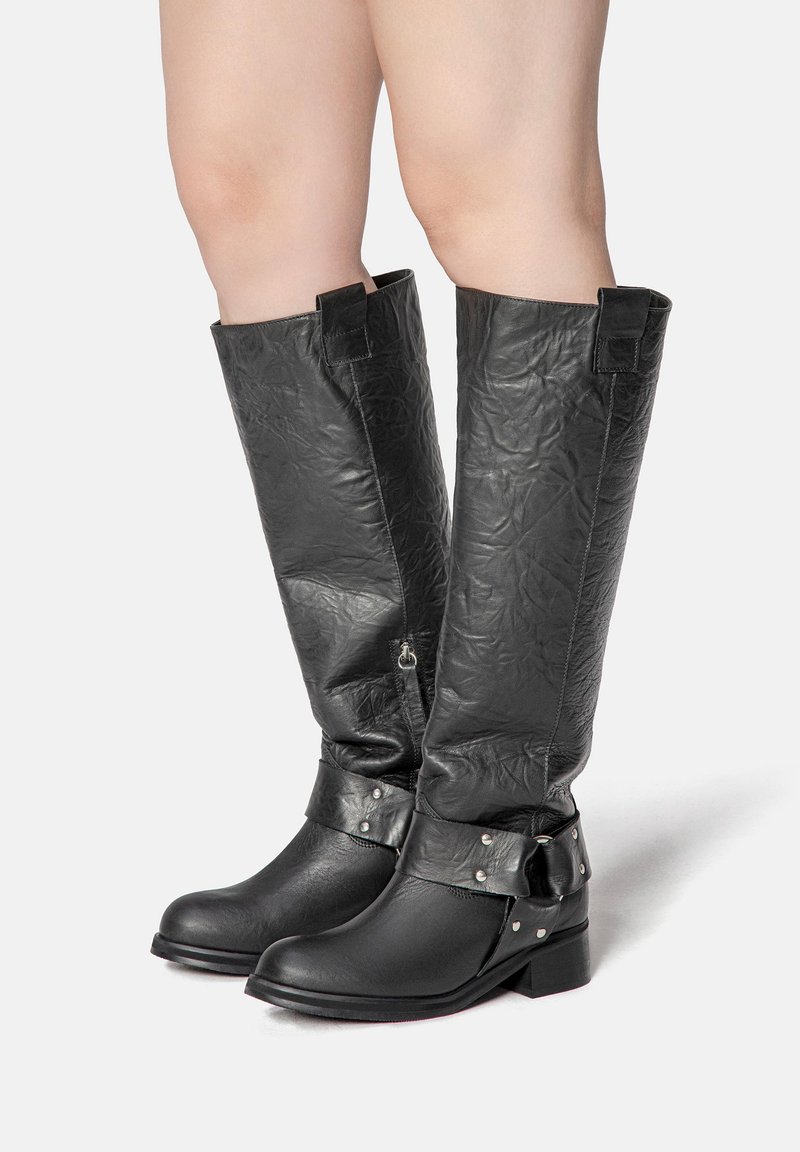 Black knee-high boots made of textured leather with a smooth toe, ankle straps, silver studs, and a low block heel.