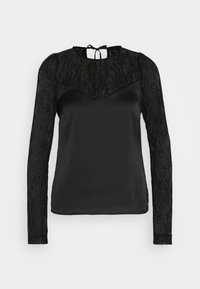 Blouse noire à manches longues avec manches en dentelle et partie supérieure de la poitrine, empiècement en dentelle florale transparente, et fermeture par lien au niveau de l'encolure arrière.