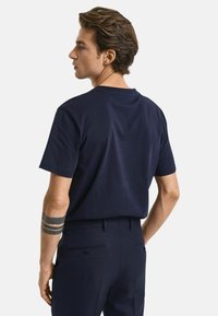 Navyblauwe katoenen T-shirt met korte mouwen en een ronde hals, gecombineerd met slim fit broeken met achterzakken en knoopdetails.