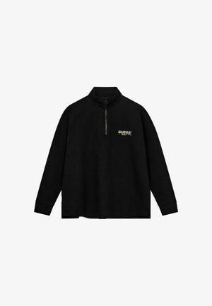 Pull noir à manches longues avec une fermeture éclair mi-longue et un logo beige « CUERA » sur la poitrine gauche, avec des poignets côtelés et un col montant.