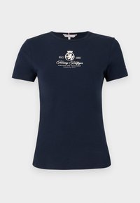 Tricou din bumbac de culoare bleumarin, cu mâneci scurte, de tip creștet, și un logo imprimat alb care prezintă un leu și o coroană. Textură moale, croială standard.