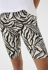Zwart-witte zebra print biker shorts, rekbaar materiaal, lengte tot halverwege het bovenbeen, aansluitend ontwerp met een gladde textuur en een elastische tailleband.