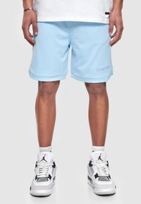 Pantalones cortos deportivos de malla azul claro con un logo bordado, con un corte recto y un ajuste holgado, combinados con zapatillas blancas.