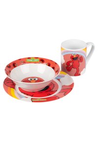 Set di stoviglie rosse che presenta Elmo di Sesame Street. Include un piatto, una ciotola e una tazza con accenti colorati e grafica da cartone animato.