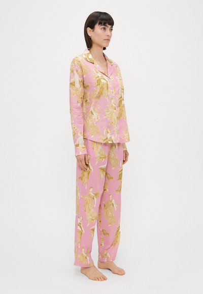 Conjunto de pijamas cor-de-rosa com estampa dourada angelical, apresentando uma blusa de botões e calças soltas, feito de um tecido macio com uma textura suave.