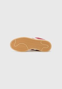 Crvene suede tenisice s bijelim detaljima, s teksturiranom gumenenom potplatom sa zig-zag uzorkom za bolji grip. Čist dizajn s minimalnim detaljima.