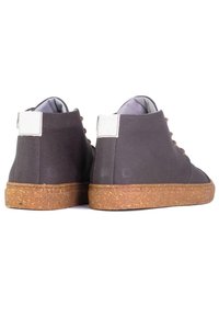 Wysokie buty wykonane z szarego płótna z teksturowaną, brązową gumową podeszwą. Posiadają białą taśmę na pięcie oraz brązowe sznurowadła. Minimalistyczny design.