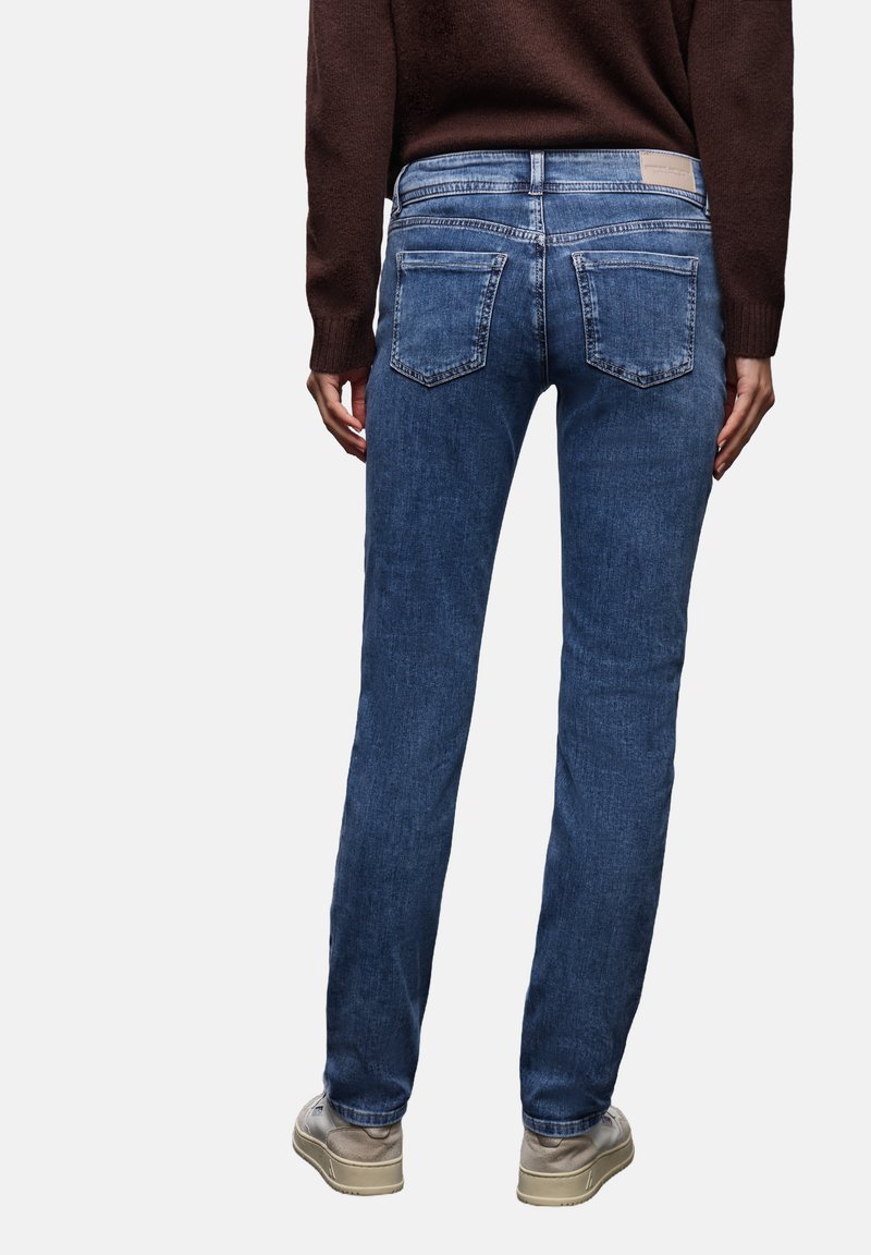 Vaqueros de mezclilla azul oscuro con corte de pernera recta, diseño de cinco bolsillos y sutiles desgastes. Presentan costuras en contraste y una etiqueta de marca en la cintura.