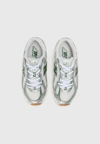 Baskets de sport argentées et vertes avec une tige en maille, des lacets blancs et une semelle extérieure texturée. Présente le logo New Balance sur les côtés.