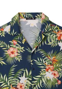 Camicia a maniche corte con bottoni, caratterizzata da uno sfondo blu scuro decorato da grandi motivi floreali e foglie in verde, rosa e bianco.