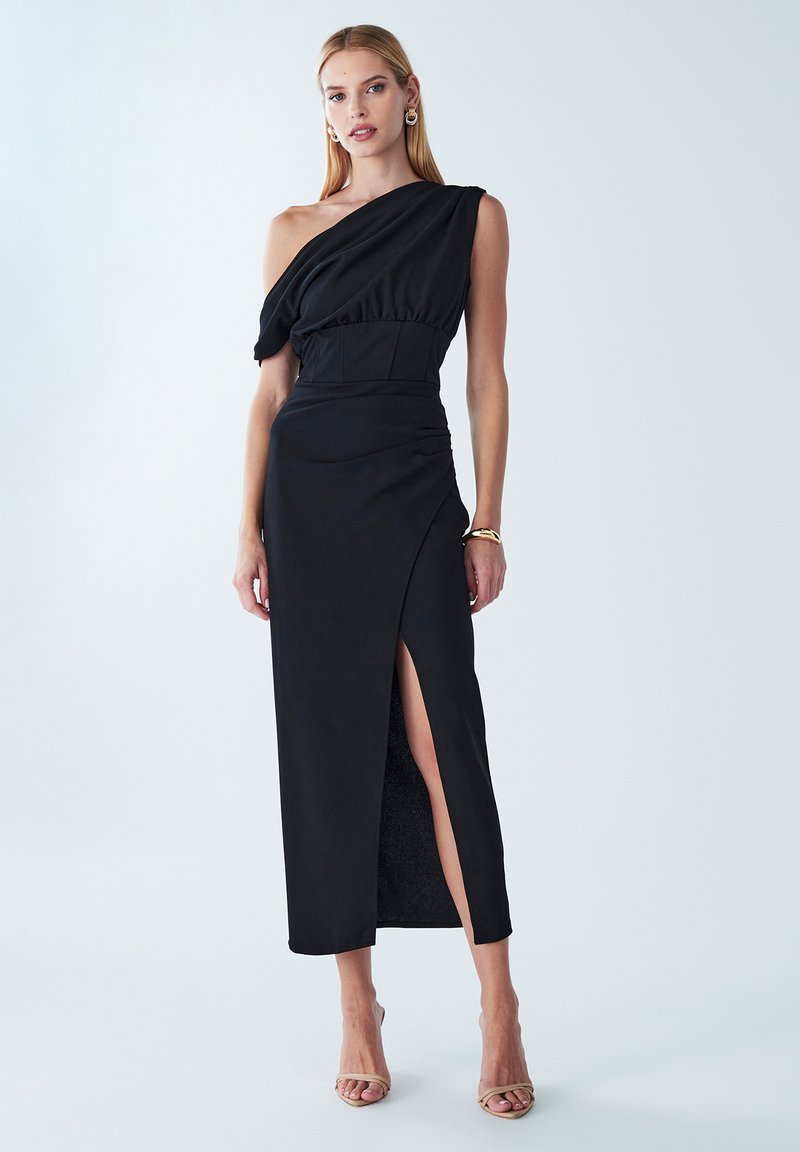 Abito nero con design a spalla unica, corpino arricciato e uno spacco laterale. Realizzato in tessuto liscio, presenta una silhouette aderente e lunghezza fino al pavimento.