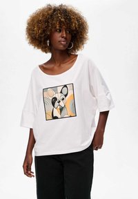 Biała bawełniana koszulka z luźnym krojem, z kolorowym, geometrycznym nadrukiem francuskiego bulldoga w kwadracie z przodu.