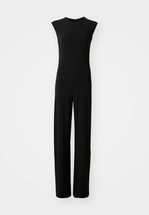 Combinaison noire avec un corsage ajusté, des manches courtes et un silhouette à jambes larges. Tissu lisse avec de subtils détails sur les côtés. Fermeture éclair dans le dos.