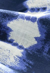 Textil s modro-bielym abstraktným vzorom s rôznymi odtieňmi. Látka má jemnú textúru s mriežkovou tkaninou.