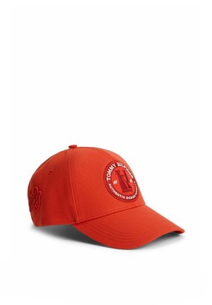 Helles rotes Baseballcap mit gebogenem Schirm, vorne mit rundem Tommy Hilfiger Logo-Patch und geprägtem Design an der Seite.