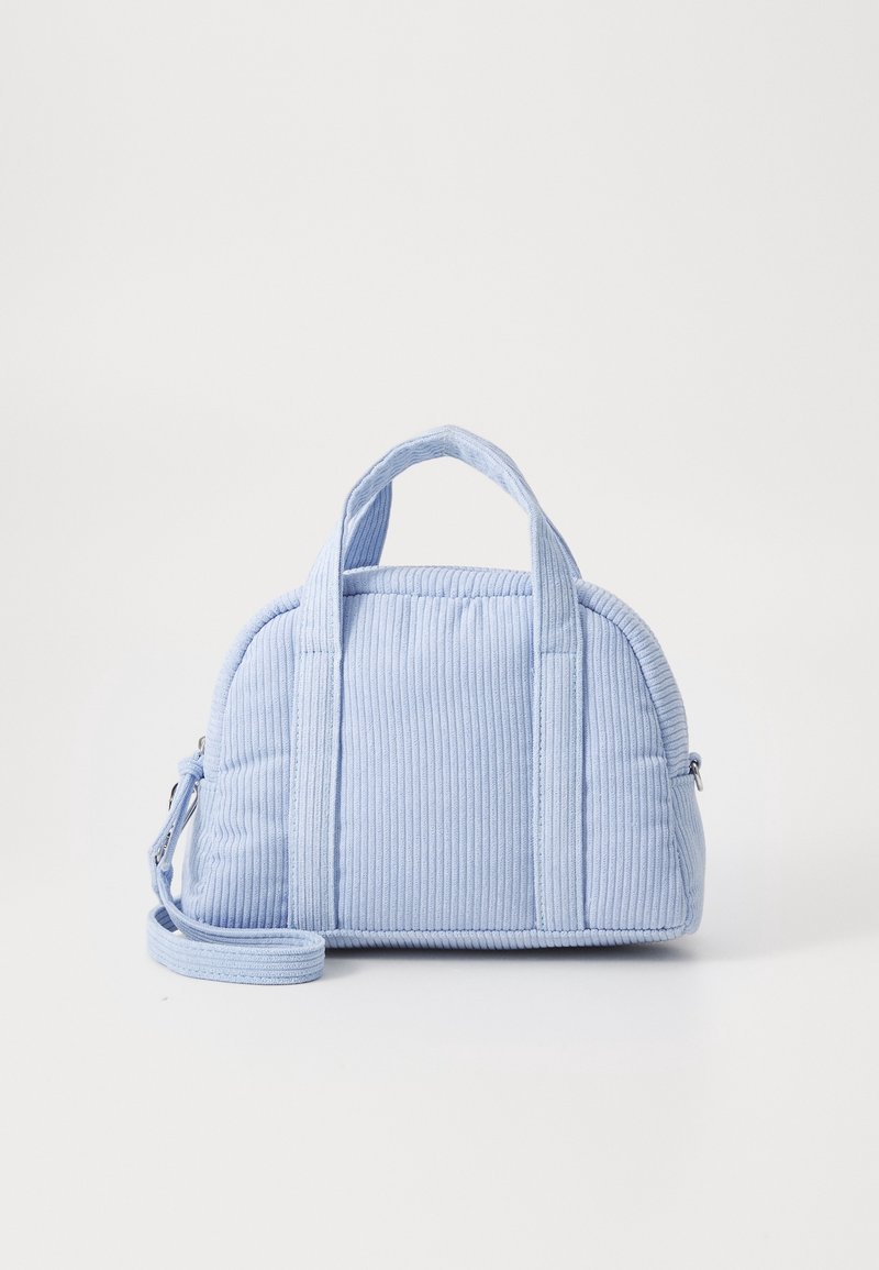 Sac à main en velours côtelé bleu clair avec deux poignées courtes, une bandoulière longue amovible et une forme rectangulaire arrondie sur un fond blanc.