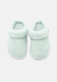 Ett par mjuka, ljusblå fleecetofflor med viktiga manschetter, designade för inomhuskomfort och värme, uppvisade på en enkel vit bakgrund.