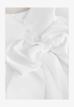 Biała satynowa sukienka na manekinie z dużą przewiązaną kokardą w talii i trzema perłowymi guzikami na gorsecie.