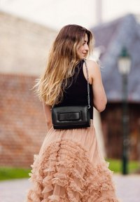 Černá kožená crossbody taška s obdélníkovým tvarem a předním klopovým zapínáním, vybavená kovovým řetízkem a diskrétním embosovaným logem.