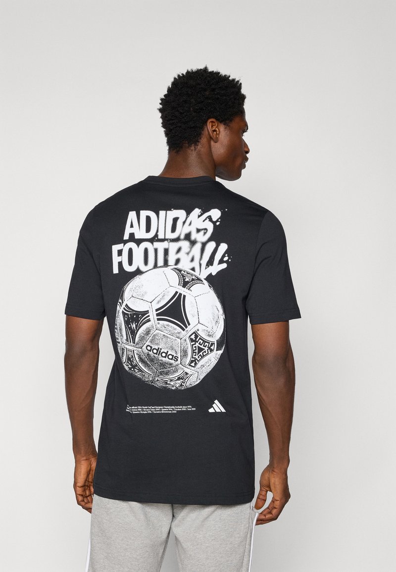 Crna pamučna majica s velikim bijelim grafičkim prikazom nogometne lopte i natpisom "ADIDAS FOOTBALL" na leđima. Kratki rukavi, okrugli ovratnik.