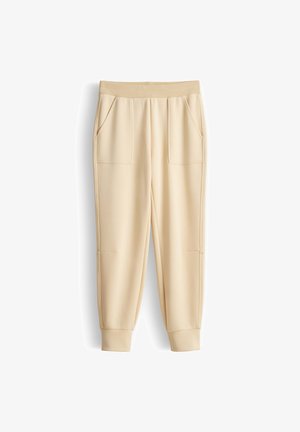Beige legere Jogginghosen mit elastischem Bund, zwei vorderen aufgesetzten Taschen und Bündchen an den Knöcheln.