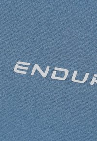 Blaues strukturiertes Gewebe mit einem auffälligen weißen "ENDURE"-Logo. Das Material sieht glatt und dehnbar aus, geeignet für Sportbekleidung.