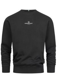 Sudadera negra con cuello redondo y puños de canalé. Presenta un logo blanco en el pecho y una tela texturizada. Diseño informal.