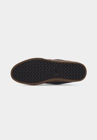 Shoe sole with black rubber tread featuring triangular pattern and brown outer edge, shown against a plain white background.