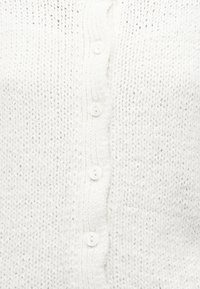 Λευκό πλεκτό ύφασμα με ραβδωτό κάθετο κουμπότρυπα με τέσσερα μικρά λευκά κουμπιά.