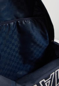Zaino navy con un motivo interno a righe testurizzate. Presenta un compartimento con zip e cuciture decorative all'esterno.