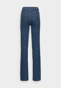 Blå denimjeans med rak passform, presenterande bakfickor, synlig sömnad och etikett på midjan.