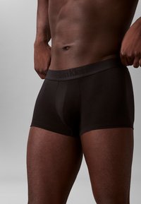 Czarne bokserki Calvin Klein z rozciągliwej bawełny z szerokim pasem z wytłoczonym logo, dopasowany krój oraz gładka tekstura.