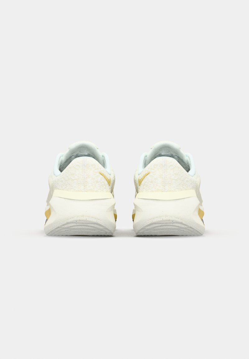 Białe buty do biegania z jasnoniebieskimi akcentami, charakteryzujące się teksturowaną cholewką, grubą piętą i złotymi detalami po bokach.