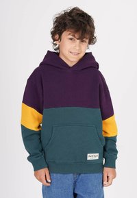 Färgblockerad huvtröja med en lila övre del, turkos kropp och gula ärmar. Har en framficka och ribbade mudd. 