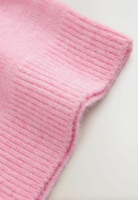 Tessuto rosa a coste con una consistenza morbida e pelosa. Il materiale appare spesso e caldo, con leggere variazioni di colore e motivo.