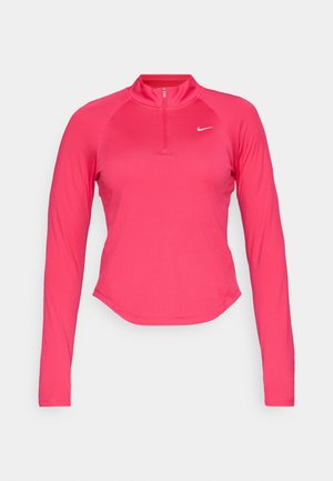 Langermet treningstopp i lys rosa stoff med halvmansjett og Nike-logo på brystet. Har en figurnær design og buet nederkant.