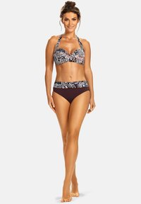 Zestaw bikini z wzorzystym topem na ramiączkach i poduszkami, w połączeniu z jednolitymi brązowymi majtkami. Materiał jest gładki i dopasowany.
