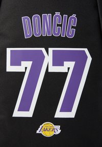 Fekete kosárlabda mez, amelyen a "DONČIĆ" felirat lila betűkkel szerepel, a "77" szám fehér és lila színekben, a "LOS ANGELES LAKERS" logóval.