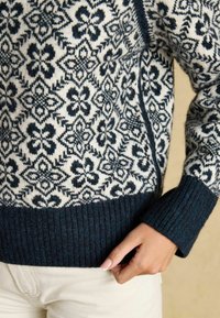 Strickpullover in Creme und Marineblau, mit floralem Muster. Gerippter Saum und Bündchen in Marineblau, mit einer strukturierten Oberfläche.