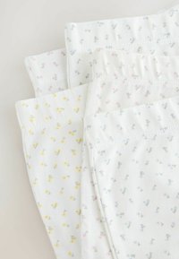 Vier paren witte katoenen slips met delicate bloemenprints in roze, geel en blauw, met zachte elastische tailles.
