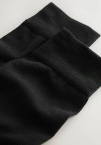Černé pletené ponožky s vroubkovaným lemem, které ukazují hladkou strukturu a jednobarevný design, složené tak, aby odhalily jemnou tkaninu a detaily tvarování.