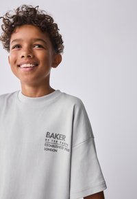 Lichtgrijs katoenen T-shirt met een ronde hals en korte mouwen, met zwart bedrukt tekst op het linkerborstgebied.