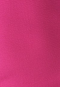 Tissu texturé fuchsia avec un motif ondulé. Le matériau semble doux et légèrement extensible, adapté aux vêtements ou à la tapisserie.