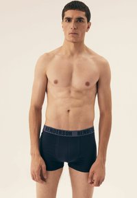 Czarne bawełniane bokserki z szarym elastycznym paskiem w talii, na którym powtarza się nazwa marki "HENDERSON".