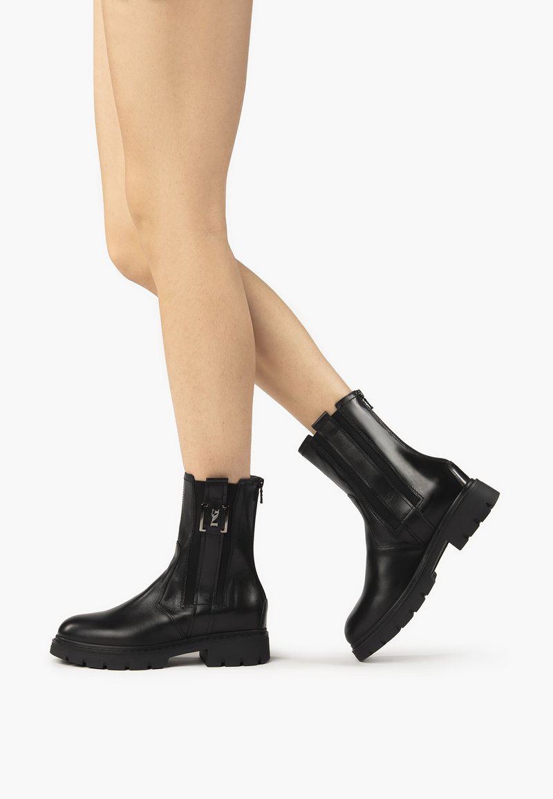 Schwarze Lederstiefeletten mit einer klobigen Sohle, Reißverschluss und vertikalen Akzenten. Glatte Textur mit einem klaren, modernen Design.