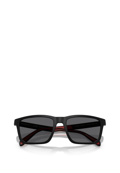 Lunettes de soleil rectangulaires noires avec verres foncés, monture mate et accents rouges sur les branches intérieures. Texture lisse et design angulaire.