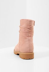 Růžové semišové kotníkové boty se skládáním, hladkým povrchem a hnědou gumovou podrážkou. Obsahují zadní zip pro snadné obouvání.